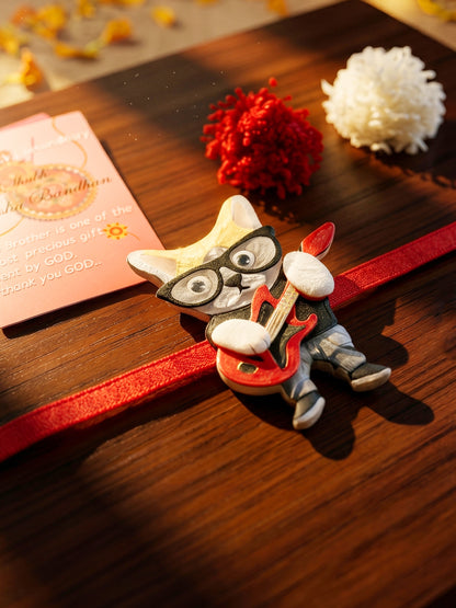 Kids Rakhi: Cute Rockstar Cat Playing Guitar Acrylic Charm on Red Ribbon, Roli, Chawal & Card (440-CHR1-1192-1-2026)
